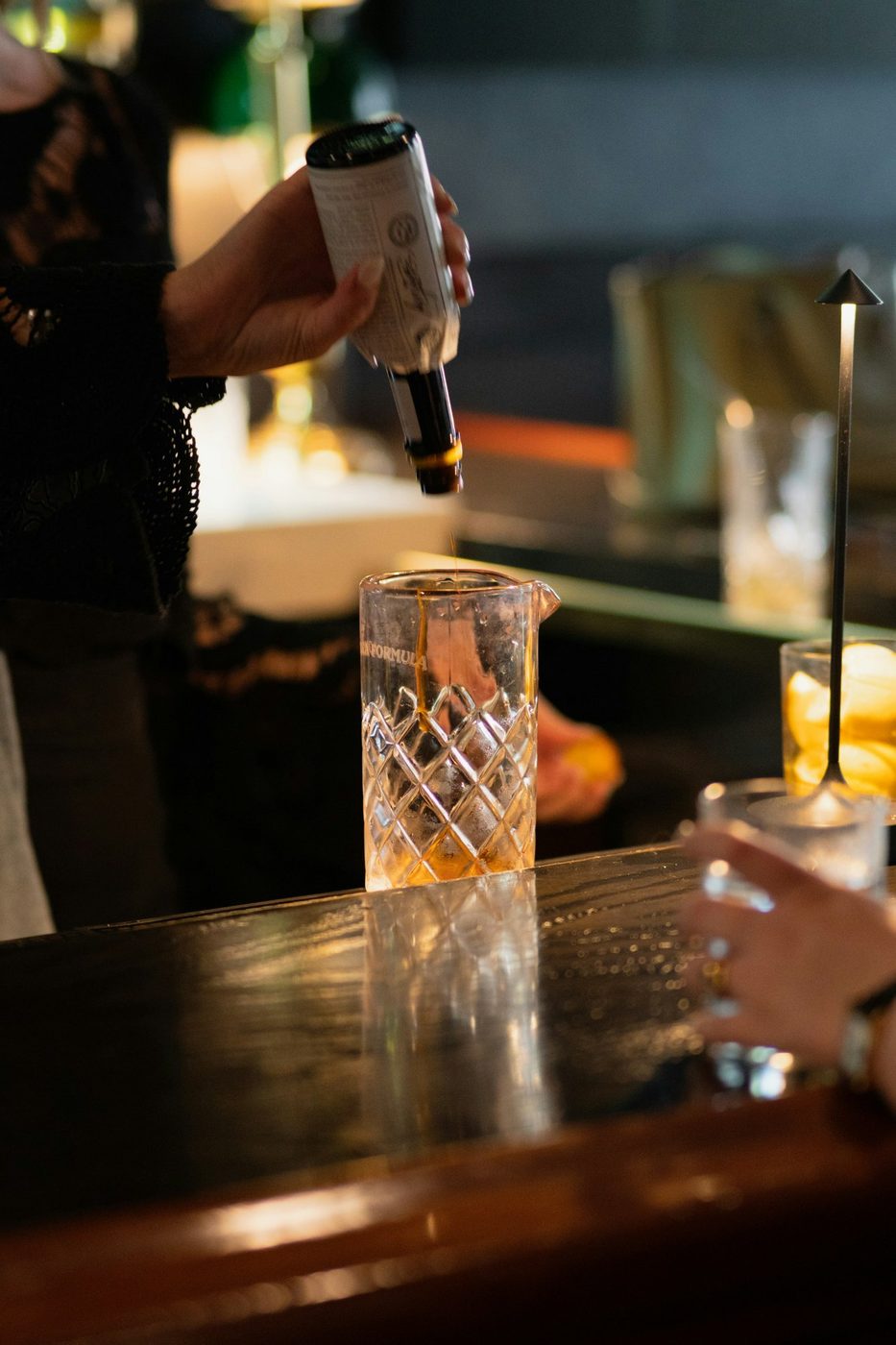 Bartender pouring bitters into a mixing glass