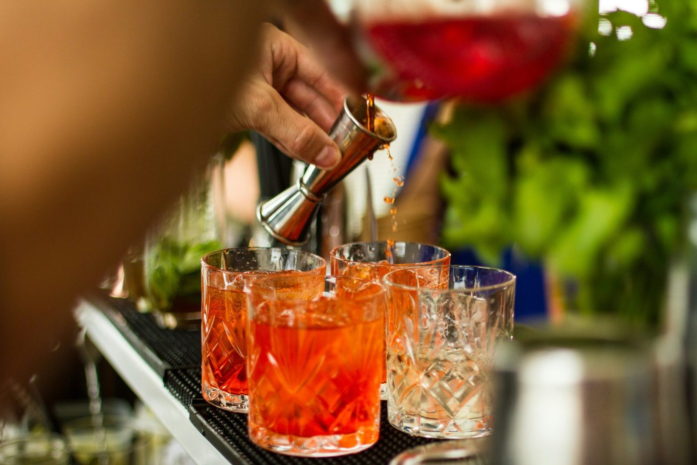 Bartender pouring cocktails into several crystal glasses